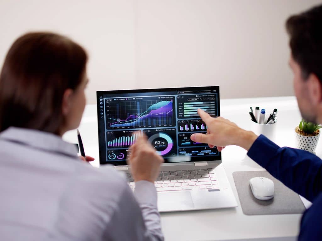Un homme et une femme regardant les KPIs de leur entreprise sur un ordinateur